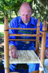 a man demonstrates a herringbone cane weaving technique